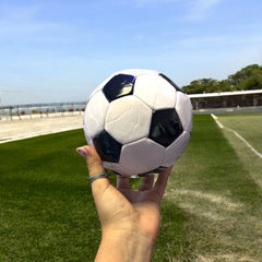 Balón mini de fútbol #2 sostenido en una mano para mostrar escala
