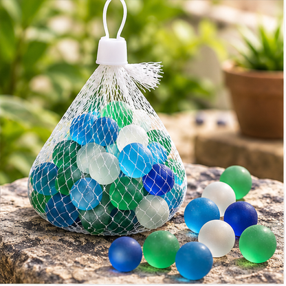 Canicas de cristal opacas de colores en bolsa de malla ambientadas sobre piedra