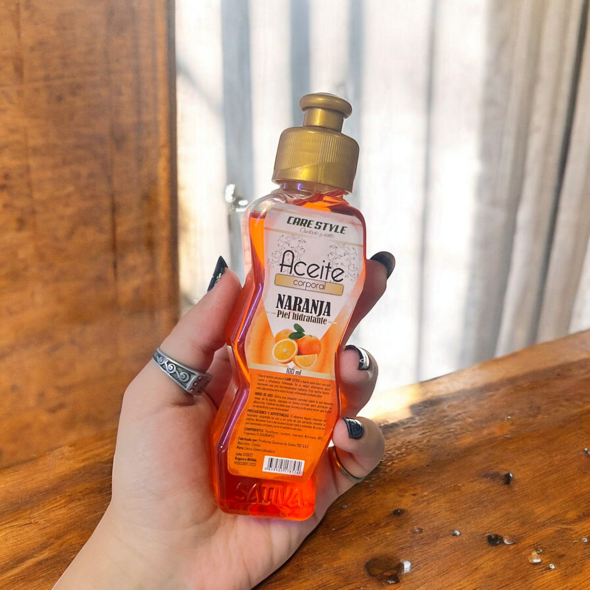 Botella de aceite corporal Sativa naranja de 100 ml sostenida en la mano