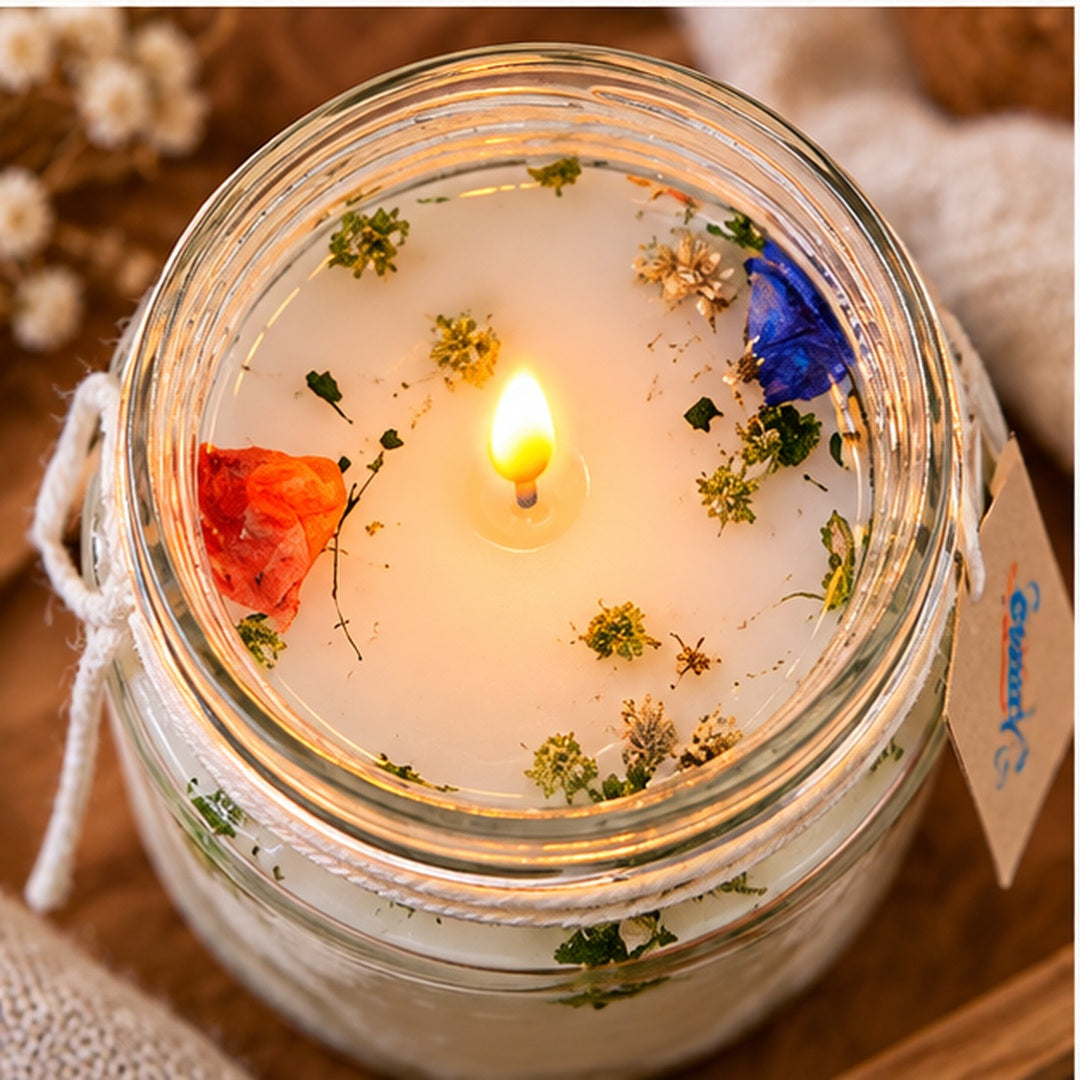 Vista superior de vela aromatizante encendida con elementos botánicos decorativos