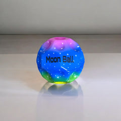 Bola de goma Moon Ball azul y multicolor de 7 cm sobre una mesa