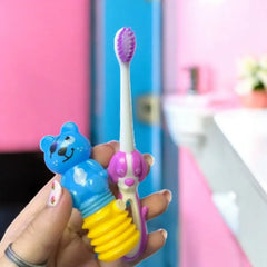 Detalle del cepillo dental infantil con cerdas moradas y mango de perro junto al dispensador de oso