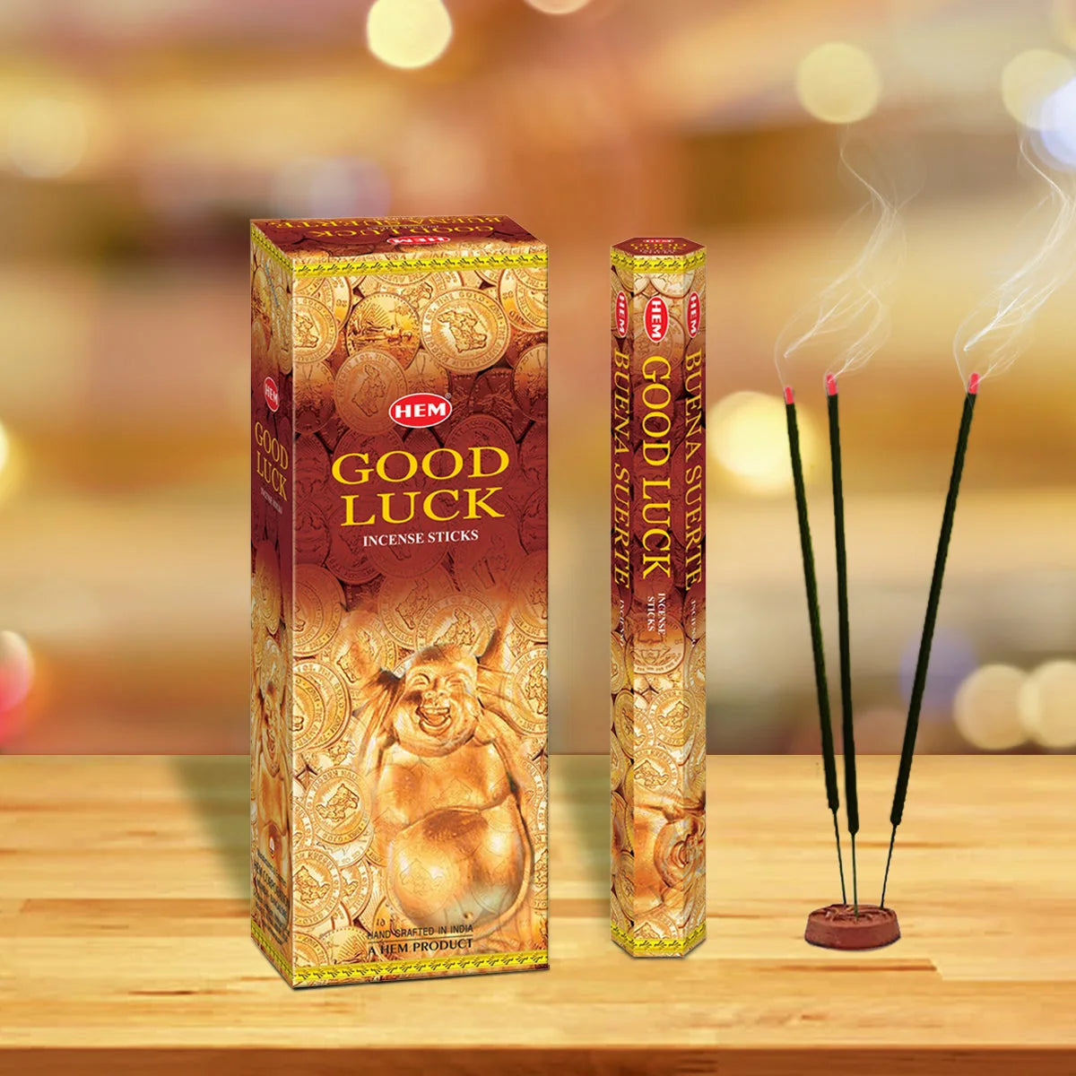 Incienso HEM Good Luck en caja hexagonal junto a varitas encendidas en un porta incienso.