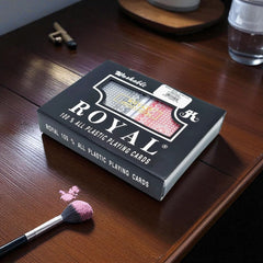 Caja Royal de cartas plásticas y baraja sobre una mesa.