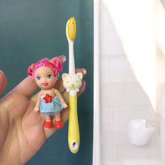 Cepillo infantil con muñeca decorativa sostenido en la mano.