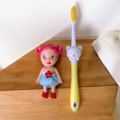 Cepillo dental infantil con muñeca decorativa, vista sobre una mesa.