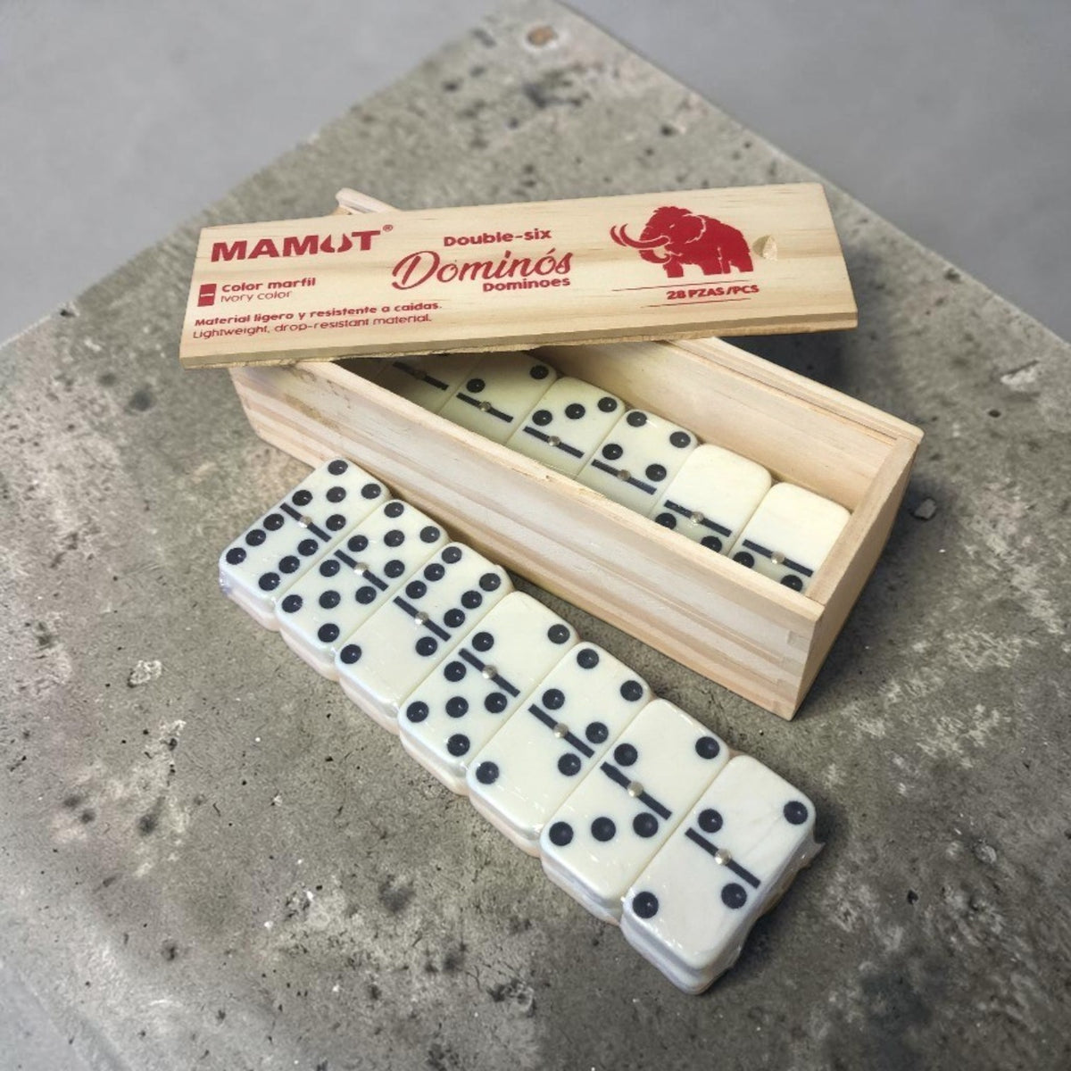 Dominó doble seis color marfil en caja de madera con tapa Mamút; fichas dispuestas para jugar.