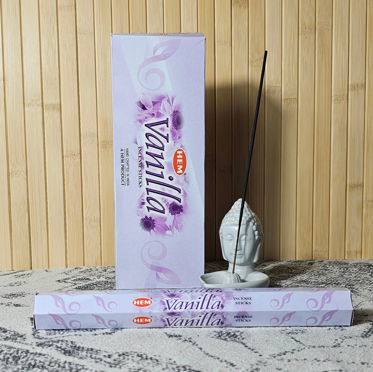 Empaque HEM Vanilla junto a un tubo y una varilla de incienso en un soporte cerámico
