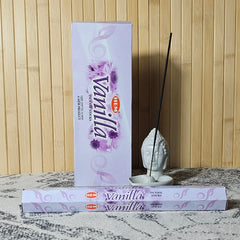 Empaque HEM Vanilla junto a un tubo y una varilla de incienso en un soporte cerámico