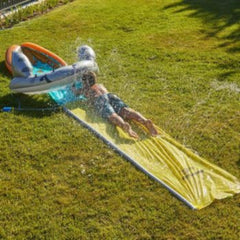 Niño deslizándose por el tobogán inflable Intex Mega Shark con rociadores